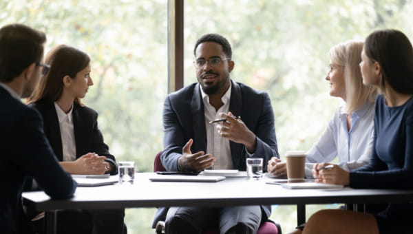 five people sitting at boardroom table in front of window