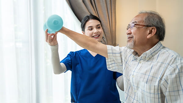 care team member helping man lift weight