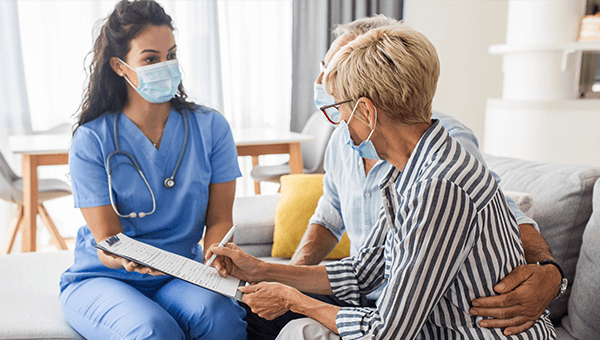 Home care worker wearing a mask sitting with client 