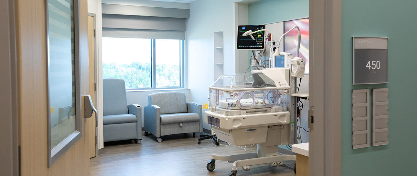 hero image size of a door opening to a NICU room, with a NICU bed and 2 lounge chairs