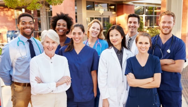 A diverse group of physicians and nurses pose for a group photo.