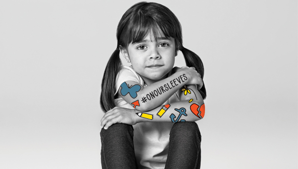 black and white photo of young girl at desk with colored stickers across her arm