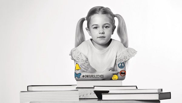 grayscale photo of young girl leaning on desk filled with books