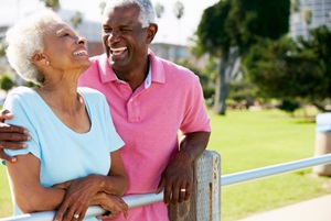 A senior couple leaning on a fence enjoying the outdoors with the man's arm around the woman