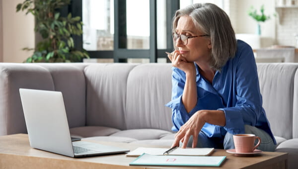 an elderly woman sitting on her couch looking at her laptop