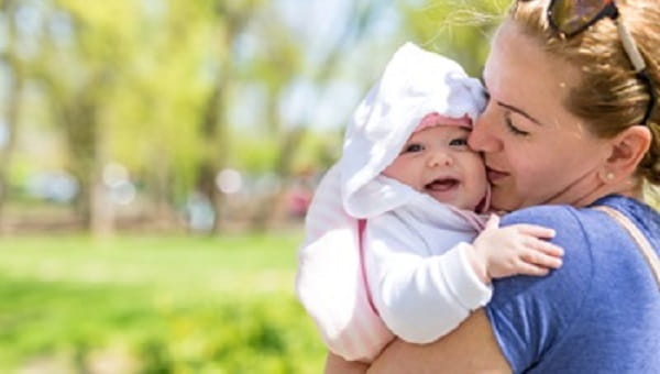 Cute baby in her mothers arms outdoors