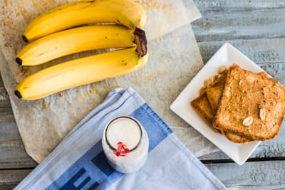 A table with toasted bread, a glass of milk, and bananas